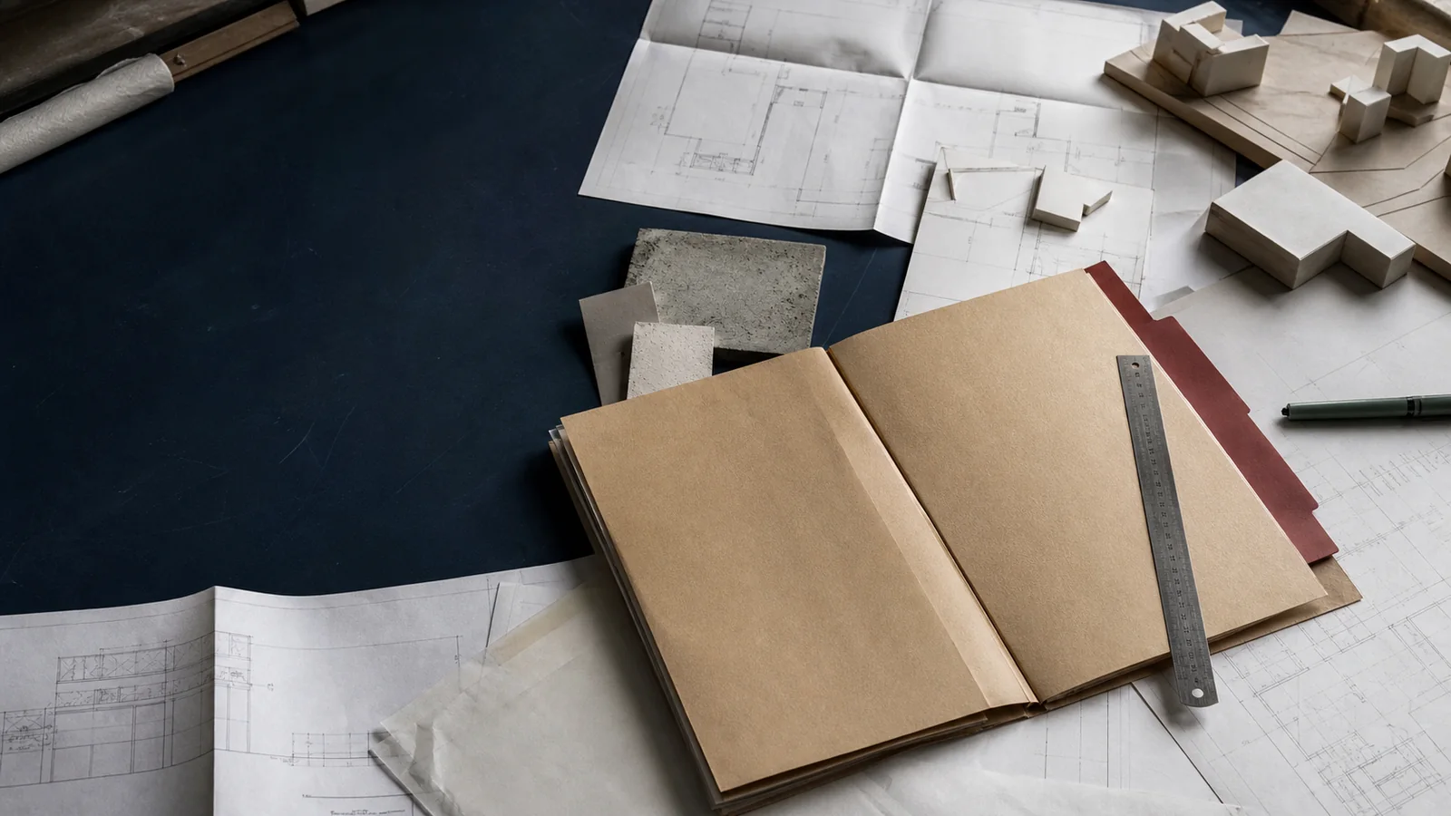 Mesa de archivo con planos, maqueta y expediente de un proyecto inmobiliario